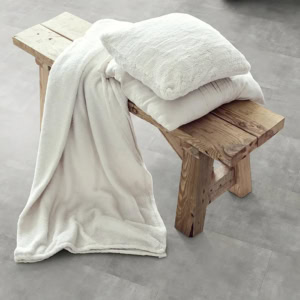 Rustic wooden bench with white pillows and draped blanket
